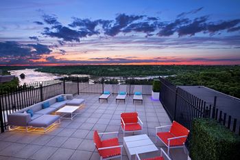 a rooftop terrace with a view of the ocean and a sunset